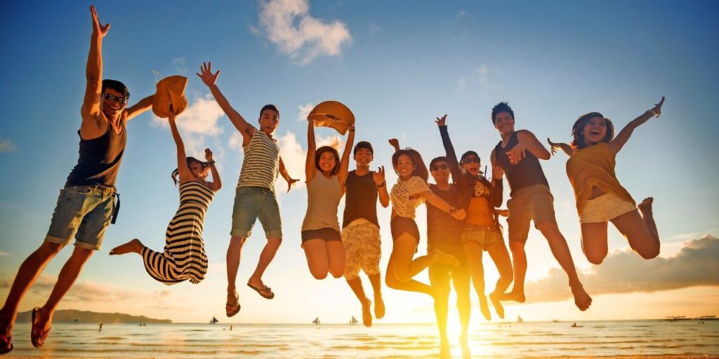 Group of young people jumping on beach